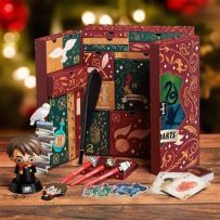 Visuel festif du calendrier de l'Avent Harry Potter ouvert, mis en scène avec un arrière-plan flou aux lumières chaudes rappelant la période de Noël. Le grand coffret déploie ses multiples tiroirs numérotés et illustrés aux couleurs de Poudlard.