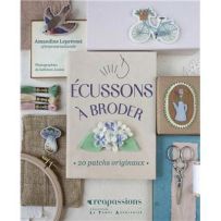 Mise en scène de la couverture du livre "Écussons à broder" entourée d'accessoires de couture (fils, ciseaux, tambour) et de superbes écussons brodés (oiseau, vélo, champignon).