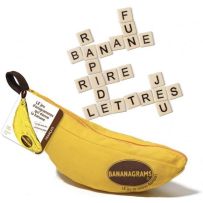 Le jeu Bananagrams illustré par sa célèbre pochette en tissu jaune vif en forme de banane, ornée du logo ovale du jeu. Une étiquette attachée à la fermeture éclair indique qu'il s'agit de la version française. Juste au-dessus, plusieurs tuiles carrées de 