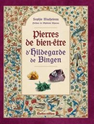 Couverture du livre "Pierres de bien-être d’Hildegarde de Bingen" de Sophie Macheteau avec encadrement orné de motifs floraux médiévaux colorés et illustration de trois pierres au centre sur fond beige.