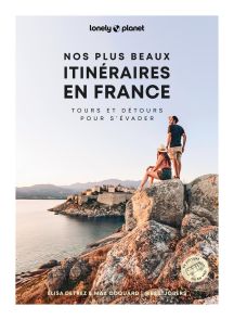 Couverture du livre Nos plus beaux itinéraires en France – Tours et détours pour s’évader publié par Lonely Planet. Photographie lumineuse représentant un homme et une femme assis sur des rochers face à la mer, avec un village fortifié en arrière-plan. Le