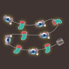 Vue de la guirlande Stitch en fonctionnement dans l'obscurité. Chaque motif (tête de Stitch et chaussette rayée) est rétroéclairé par une LED, créant une aura lumineuse jaune et chaleureuse autour des personnages.